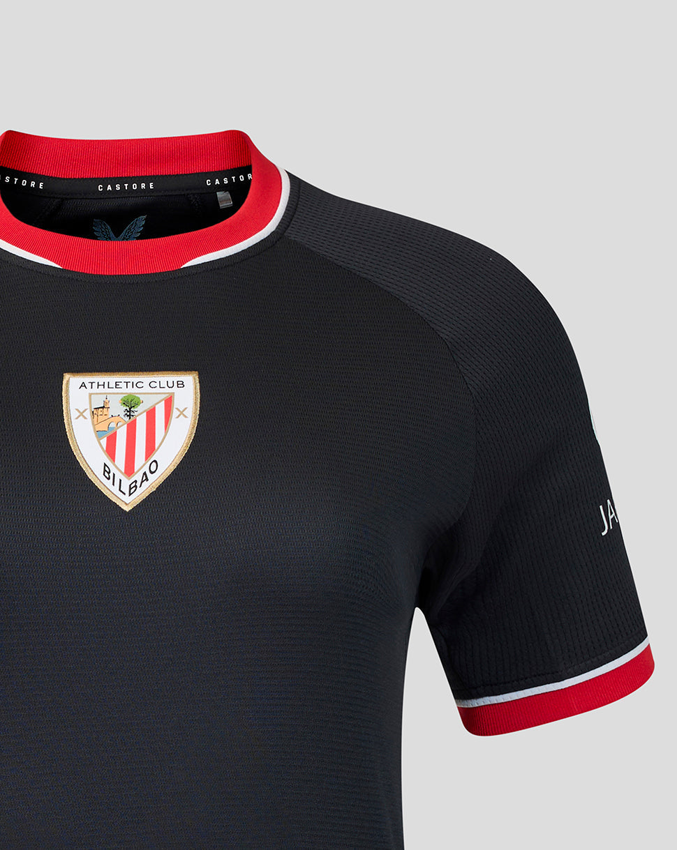 Close up of navy away shirt sleeve and chest highlighting the crest and red cuff trim.