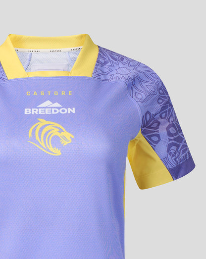A close-up of a purple and yellow athletic jersey with 'BREEDON' and a lion logo on the chest, set against a solid gray background.
