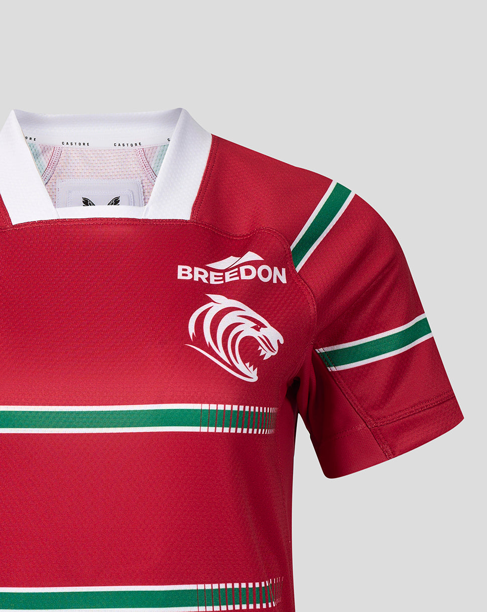 A close-up of a red short-sleeve rugby jersey with green and white stripes, featuring a white collar, the word 'BREEDON' on the chest, and a white lion logo.