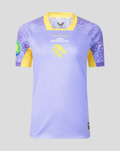 A short-sleeve soccer jersey displayed on a ghost mannequin against a light gray background. The jersey features a light lavender-purple body, yellow collar and sleeve cuffs, and a purple tribal pattern on the shoulders and sleeves.