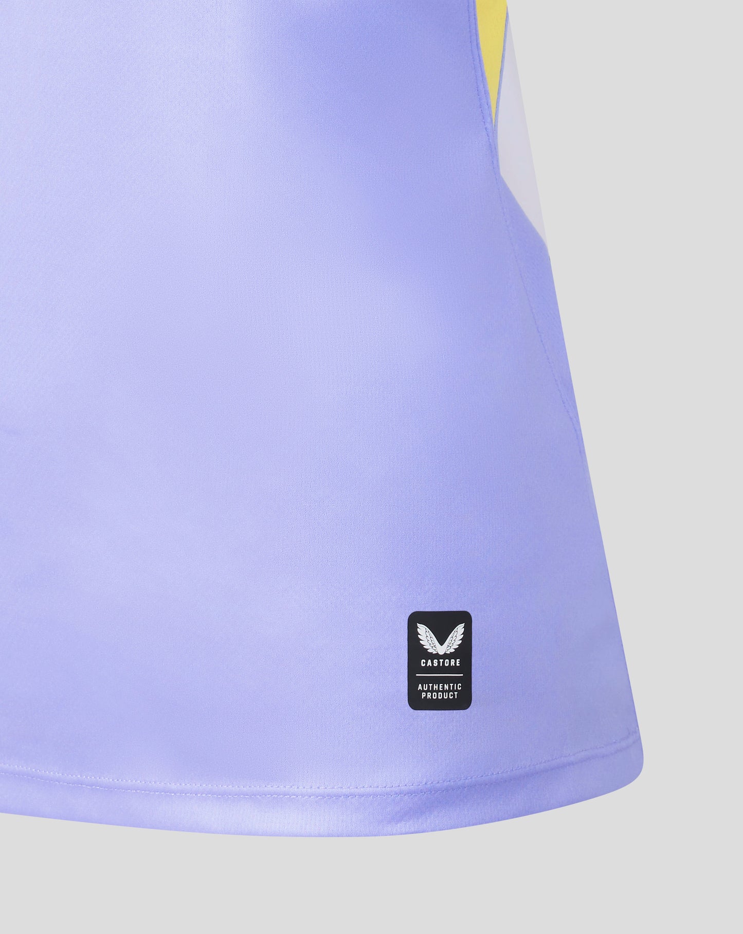 Close-up of a light purple athletic skirt with a black and white Butterfly Authentic Product label near the hem, on a light gray background.