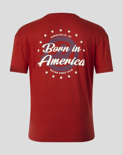 A red short-sleeve t-shirt shown from the back, featuring a white and blue graphic print that reads 'Born in America' with 'Kannapolis, NC' and 'Racing Since 2016' in circular text and star accents.