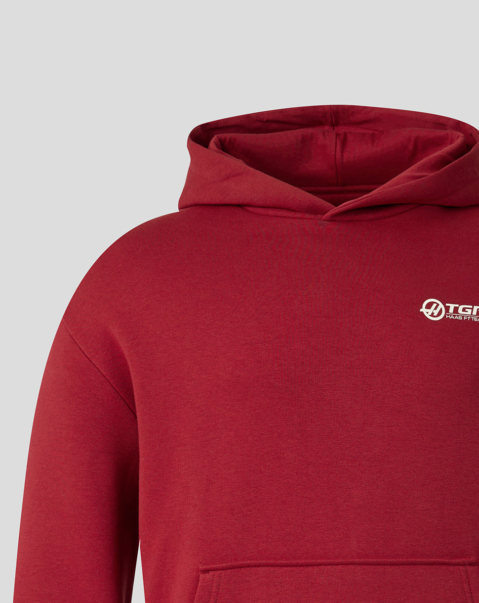 A close-up of a heathered red pullover hoodie with a small white and black TGR Global logo on the left chest, set against a solid light gray background.