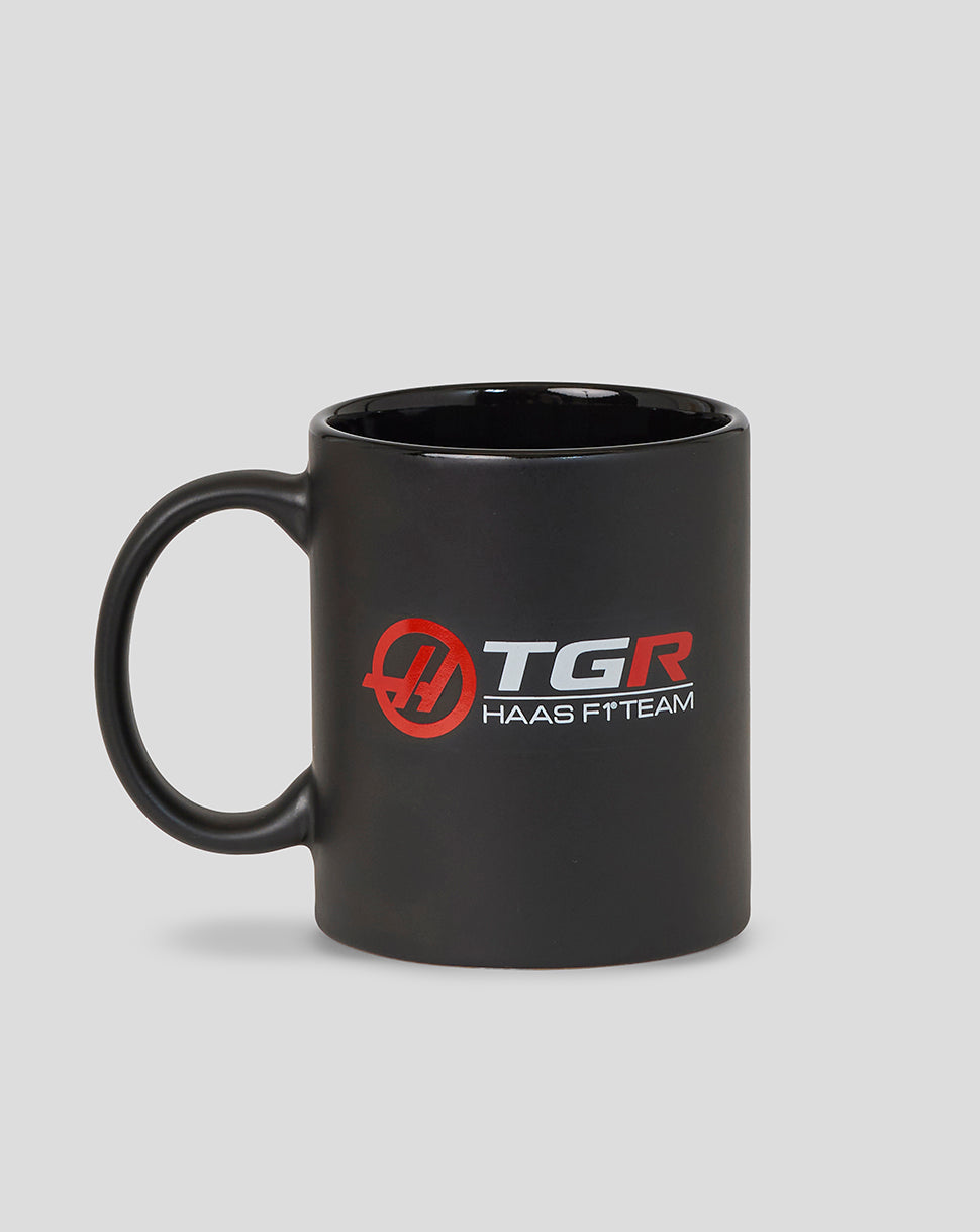 Black mug with TGR Haas F1 Team logo on a gray background