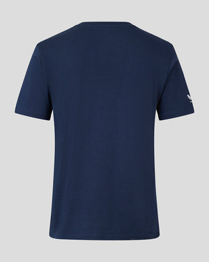 A navy blue short-sleeve t-shirt shown from the back, featuring a small white logo on the left sleeve, set against a solid light gray background.