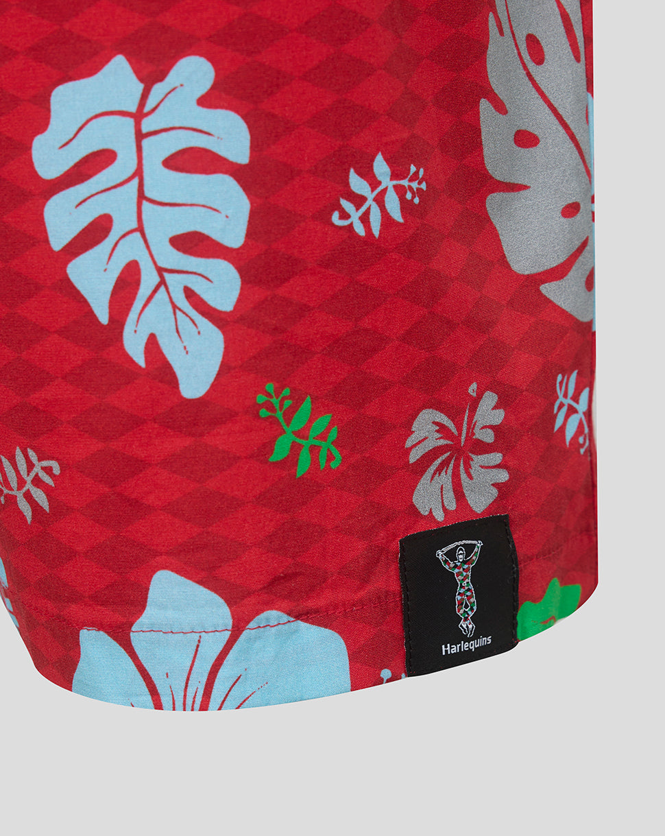 Red fabric with tropical leaf patterns and a brand label on a white background