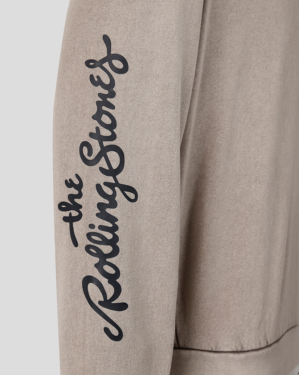 Close-up of a light beige sweatshirt sleeve featuring the black cursive script logo 'the Rolling Stones' printed vertically on the upper arm.