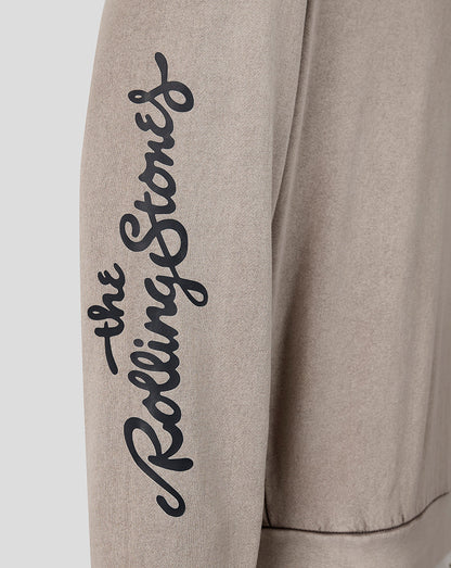 Close-up of a light beige sweatshirt sleeve featuring the black cursive script logo 'the Rolling Stones' printed vertically on the upper arm.