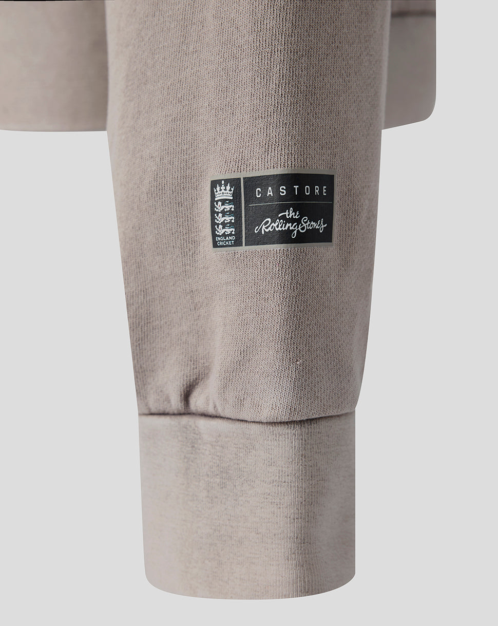 Close-up of a light taupe sweatshirt sleeve featuring a black rectangular Castore logo patch on the upper cuff.