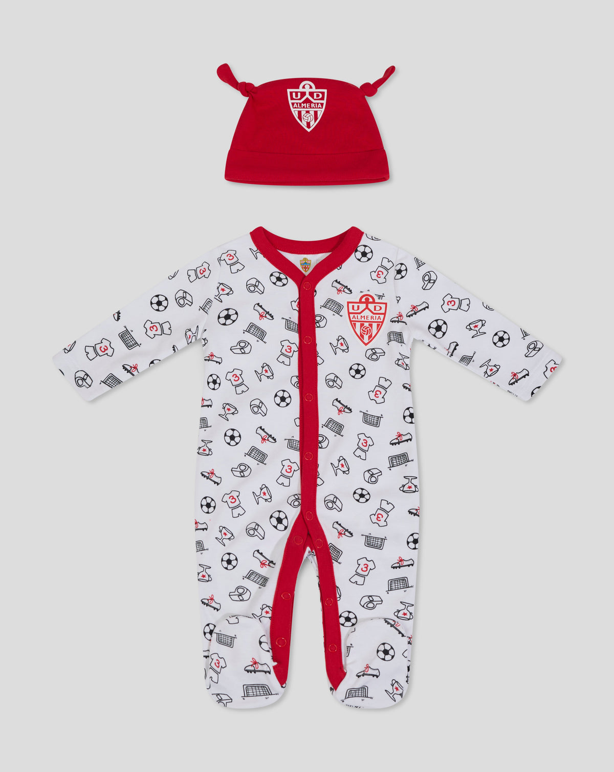 Red baby hat with crest alongside a white babygrow printed with football icons.
