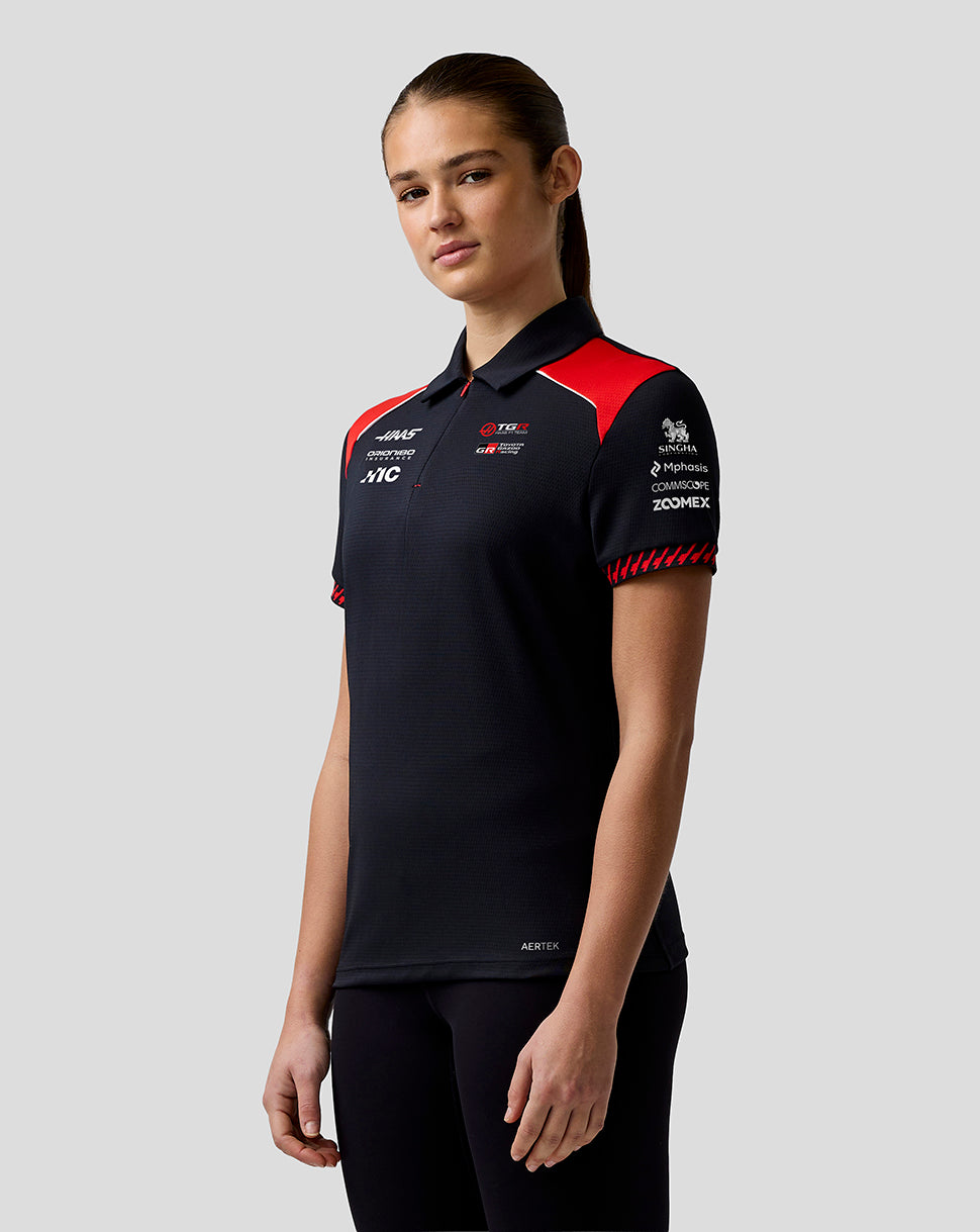 Person wearing a black and red sports jersey with various logos on a gray background
