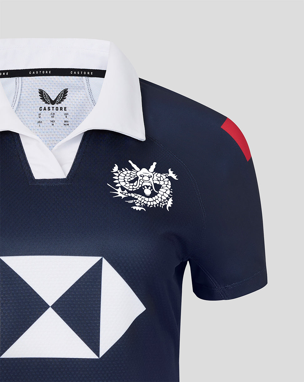 Navy blue sports jersey with white collar, dragon emblem, and geometric design on a light gray background.