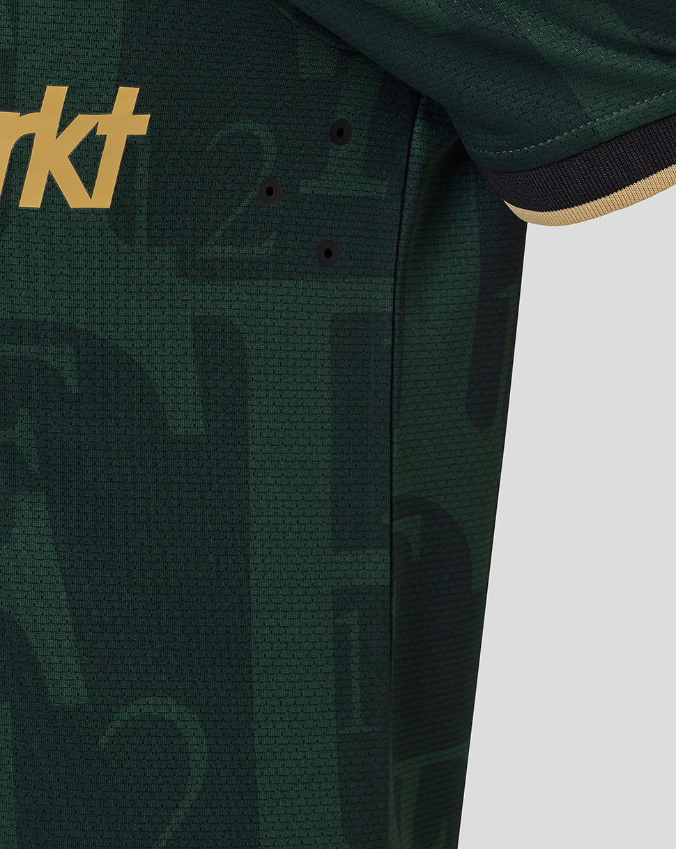 Chest detail of the green Feyenoord shirt with large gold MediaMarkt sponsor text across the front and part of the sleeve cuff.