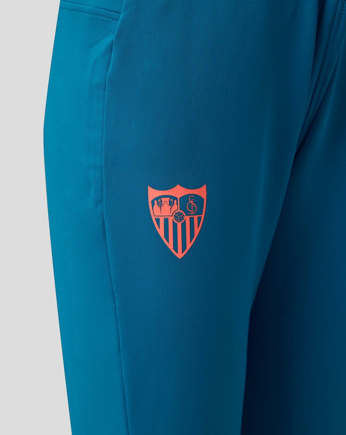 Sevilla FC junior training pants in blue with a pink club crest on the thigh