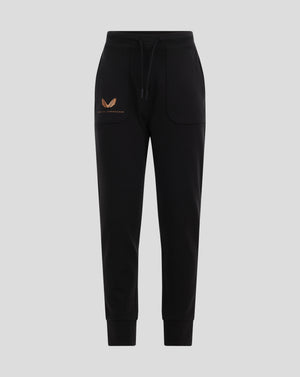 Front view of black Leverkusen travel pants with drawstring and orange emblem on the left pocket.