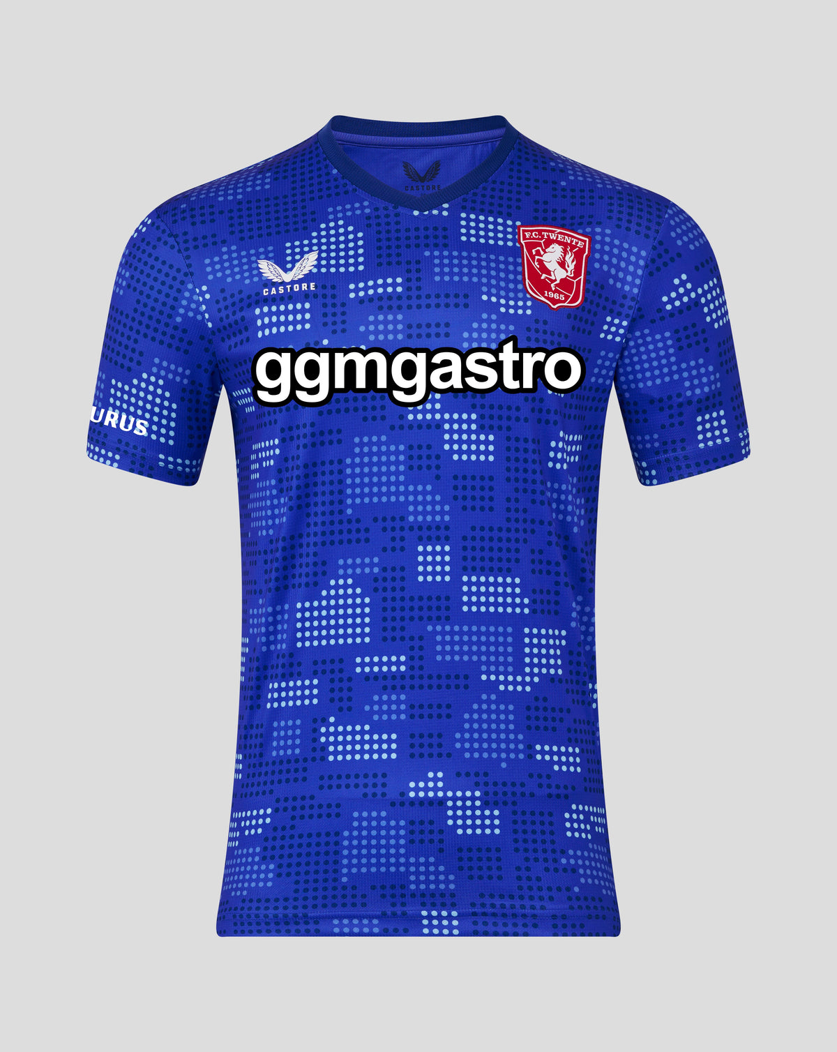 A blue short-sleeve soccer jersey with a pixelated geometric pattern, featuring a red crest on the left chest, a white logo on the right chest, and a large white 'gmgastro' text overlay across the center.
