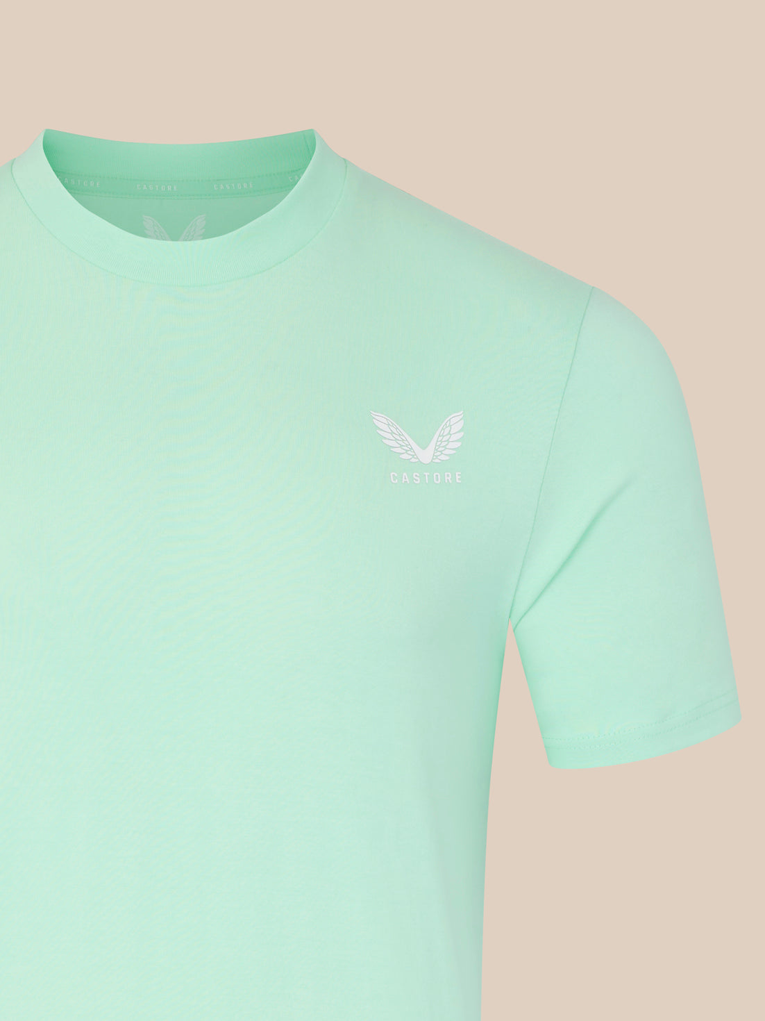 Light green t-shirt with a small logo on a beige background