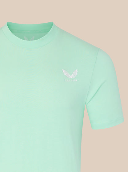 Light green t-shirt with a small logo on a beige background