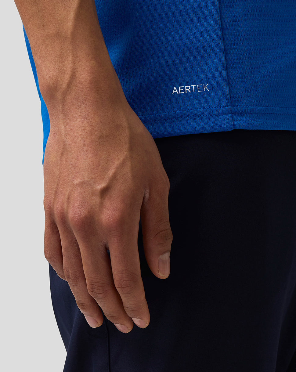 Close-up of a person wearing a blue jacket with 'AERTEK' branding, focusing on the hand and jacket.
