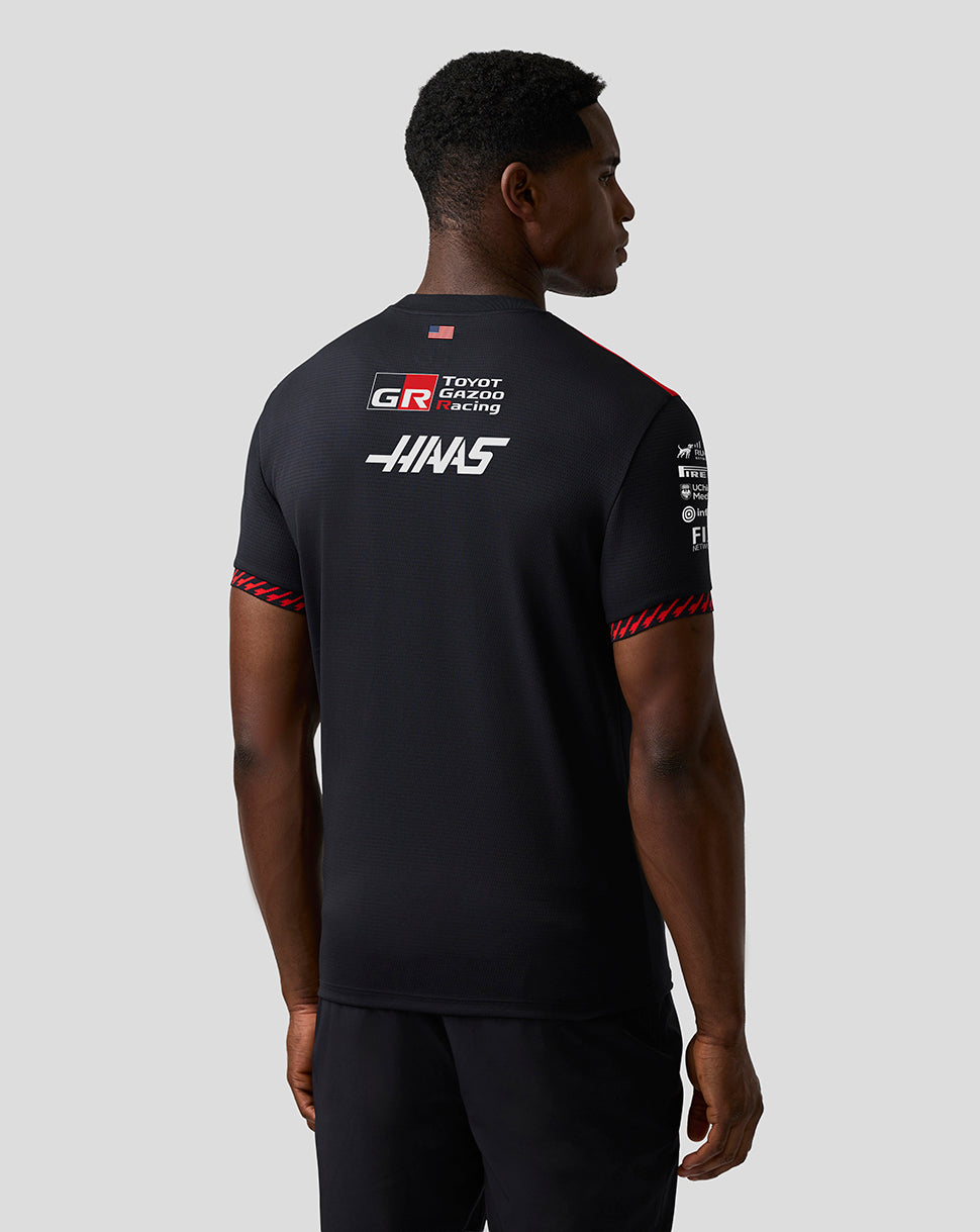 Person wearing a black Haas Formula One team shirt with logos on a gray background