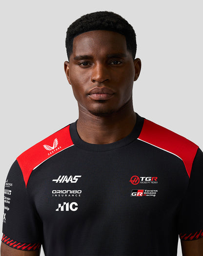 Person wearing a black and red sports jersey with various sponsor logos on a gray background