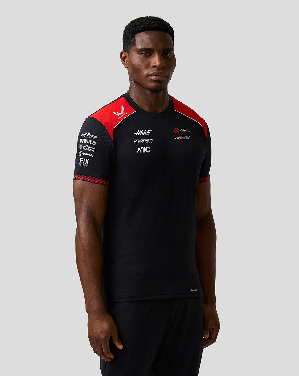 Man wearing a black sports outfit with red accents on a gray background