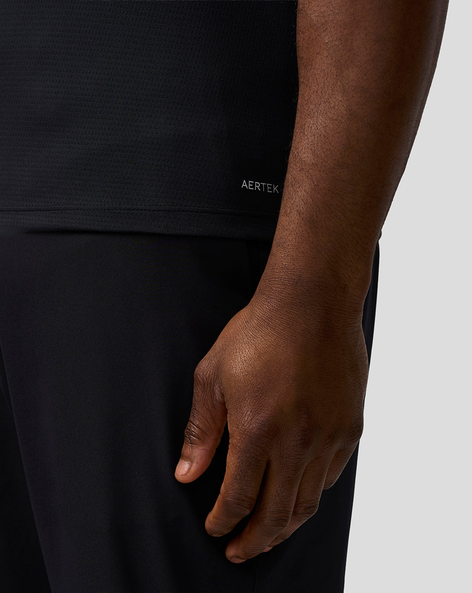 Person wearing a black outfit with 'AERTEK' branding on a neutral background