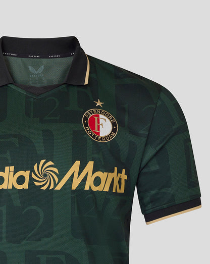 Front close-up of a green Feyenoord football shirt showing the club crest on the left chest and the gold MediaMarkt sponsor across the front.