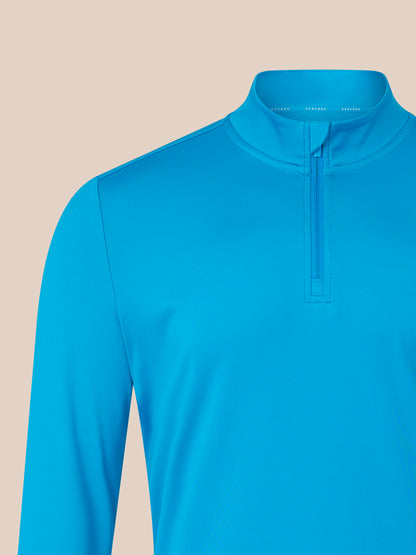 Blue long-sleeve shirt with a quarter zip on a beige background