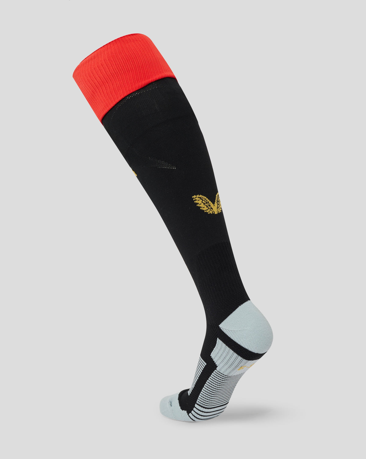 A single knee-high athletic sock shown on a cropped lower leg form against a light gray studio background. The sock is predominantly black with a bright red cuff, a small gold leaf logo near the calf, and a light gray heel and toe area with subtle dark striping.