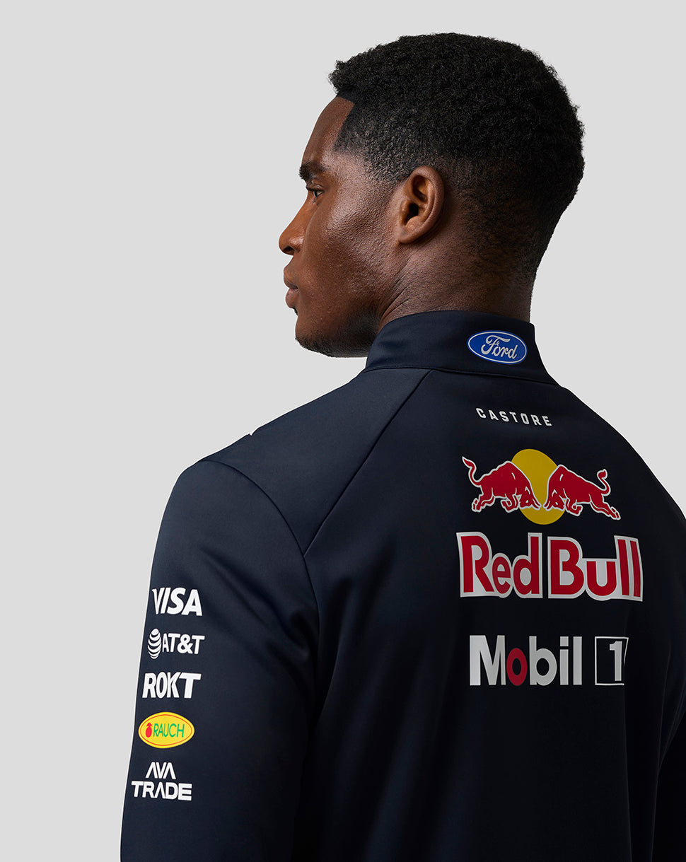 Person wearing a dark blue racing suit with Red Bull and Ford logos on a light gray background
