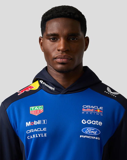 Person wearing a blue racing jacket with various sponsor logos on a gray background