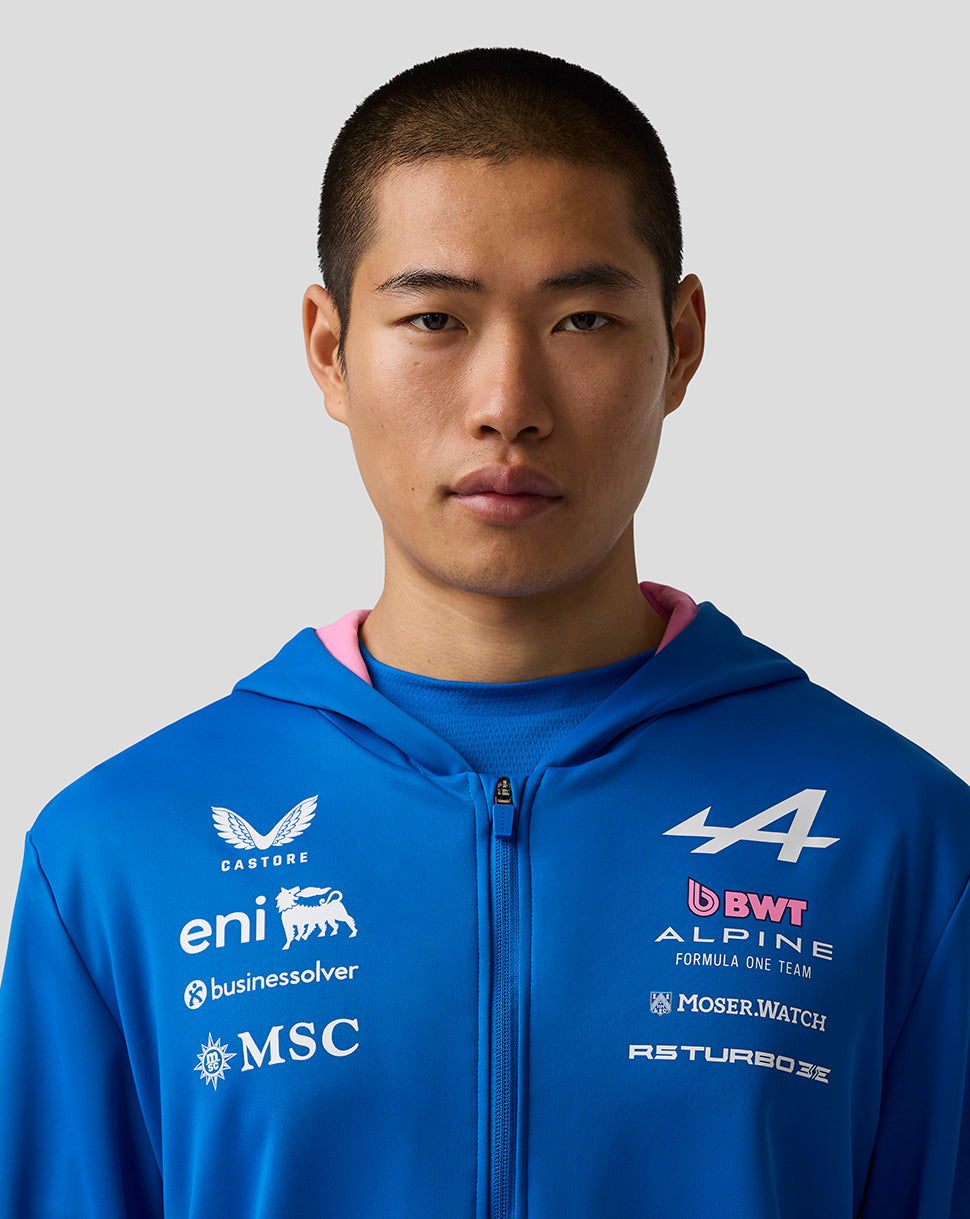 Portrait of a young man wearing the Official Junior BWT Alpine Zip Hoodie in blue with team chest logos and pink hood lining