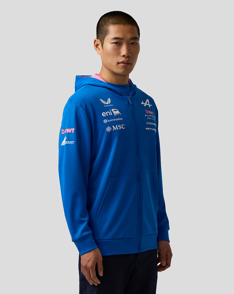 Three-quarter view of a model in a blue Official Junior BWT Alpine Zip Hoodie featuring chest and sleeve sponsor logos