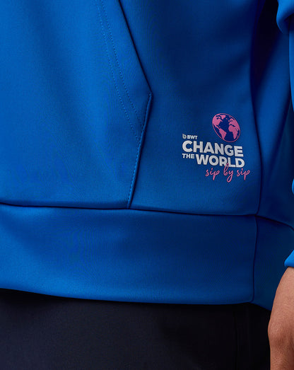 Close-up of blue hoodie fabric showing Change the World logo with pink globe near the pocket