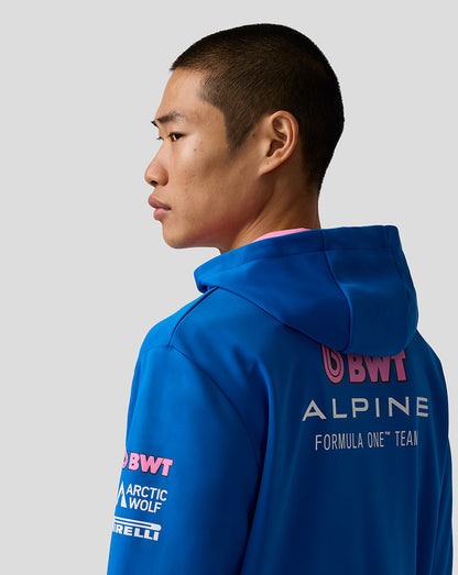 Person wearing a blue hoodie with branding on the back against a gray background