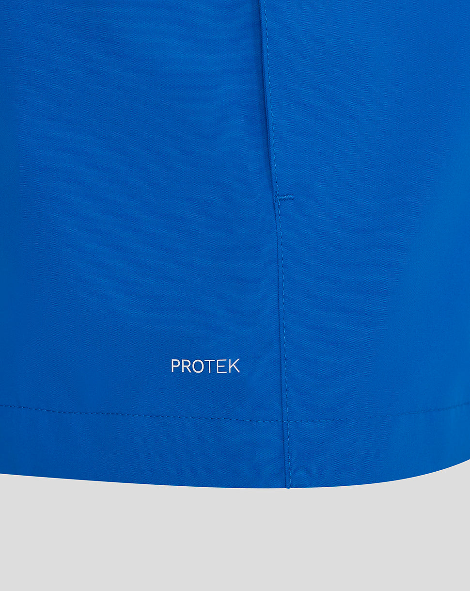 Close-up of a blue jacket with 'PROTEK' branding on a white background