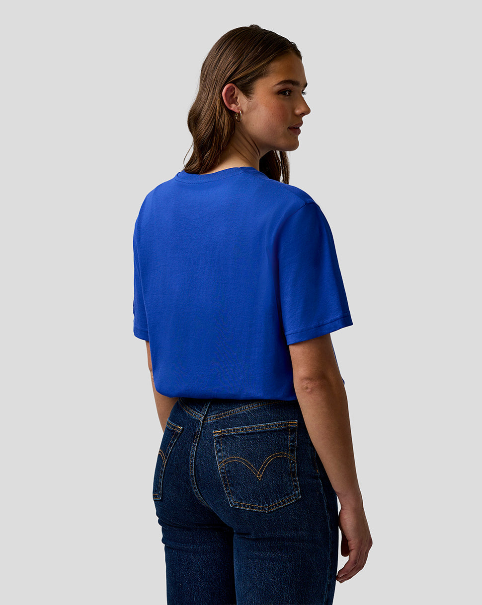 Woman wearing a blue t-shirt and dark jeans on a plain background
