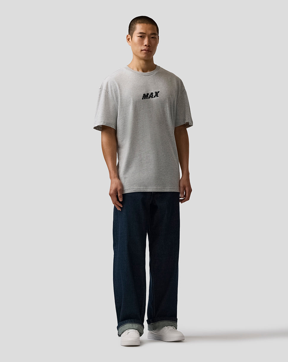 Person wearing a gray t-shirt with 'MAX' print and dark pants on a white background