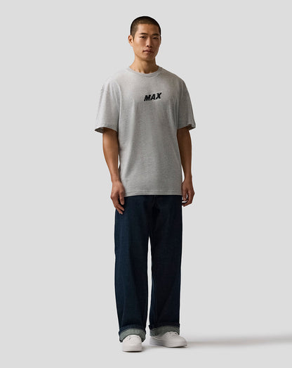 Person wearing a gray t-shirt with 'MAX' print and dark pants on a white background