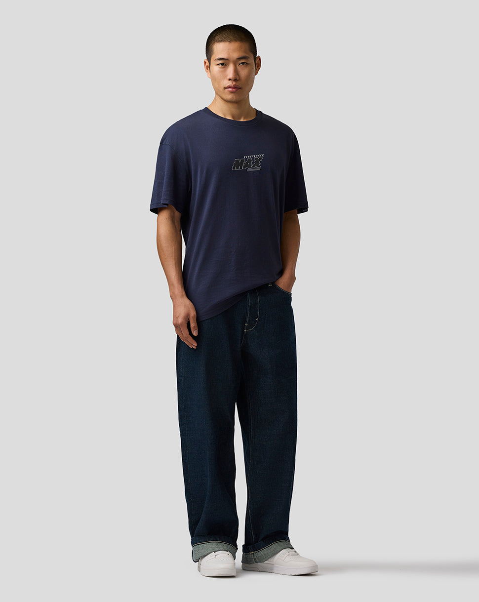 Man wearing a navy t-shirt and dark jeans on a light gray background