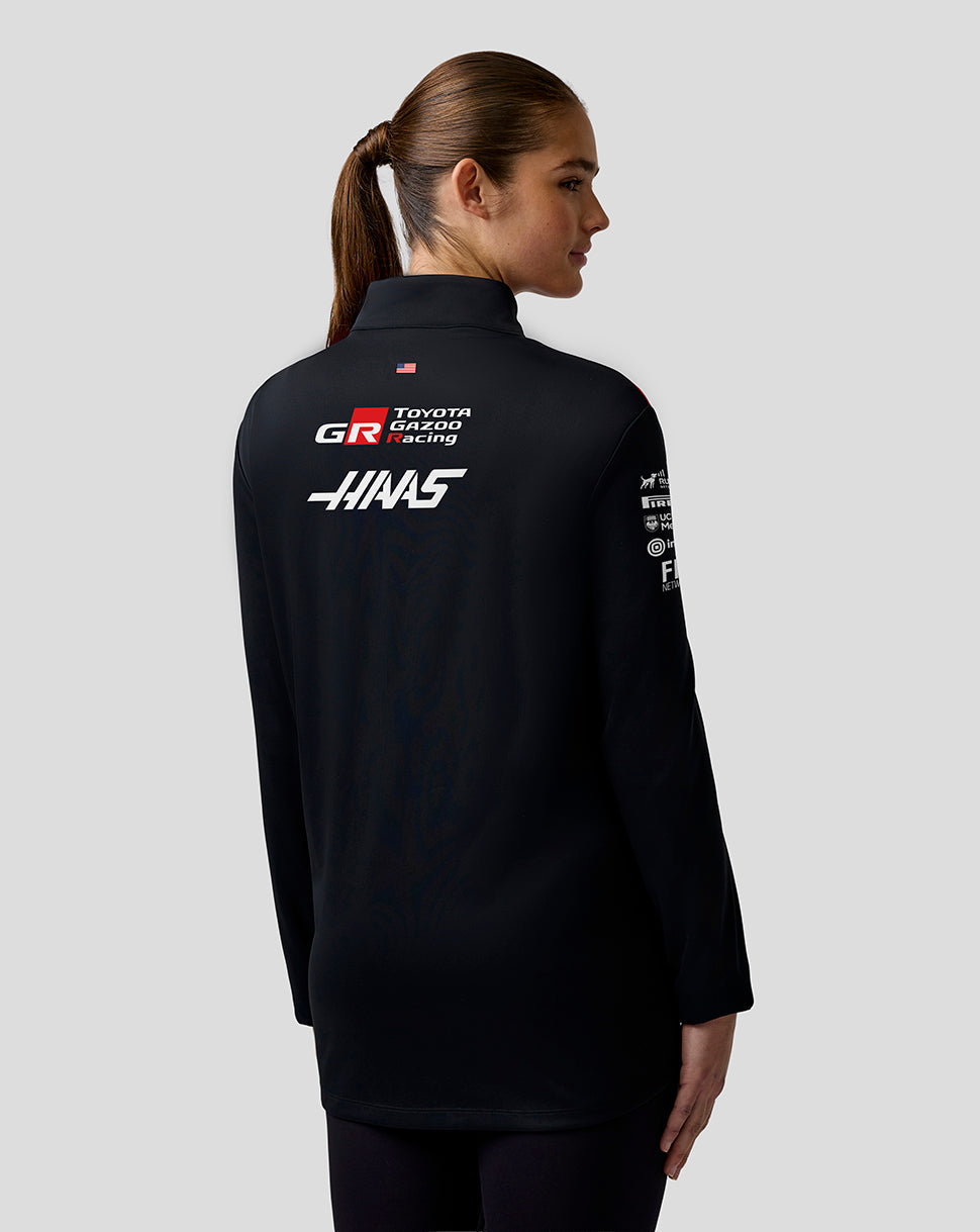 Person wearing a black jacket with Toyota Gazoo Racing and Haas logos on a gray background