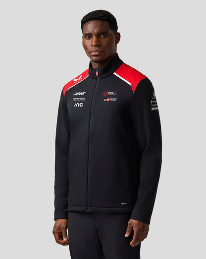 Person wearing a black jacket with red and white accents on a gray background