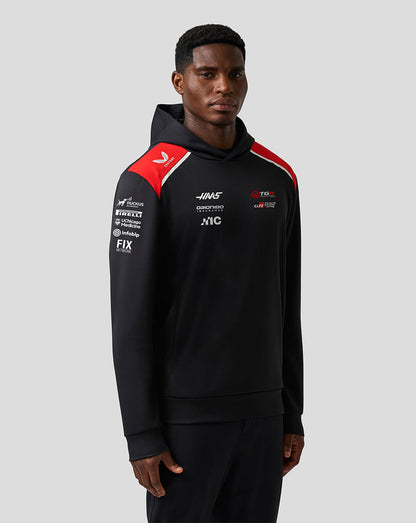 Person wearing a black hoodie with red and white accents on a gray background