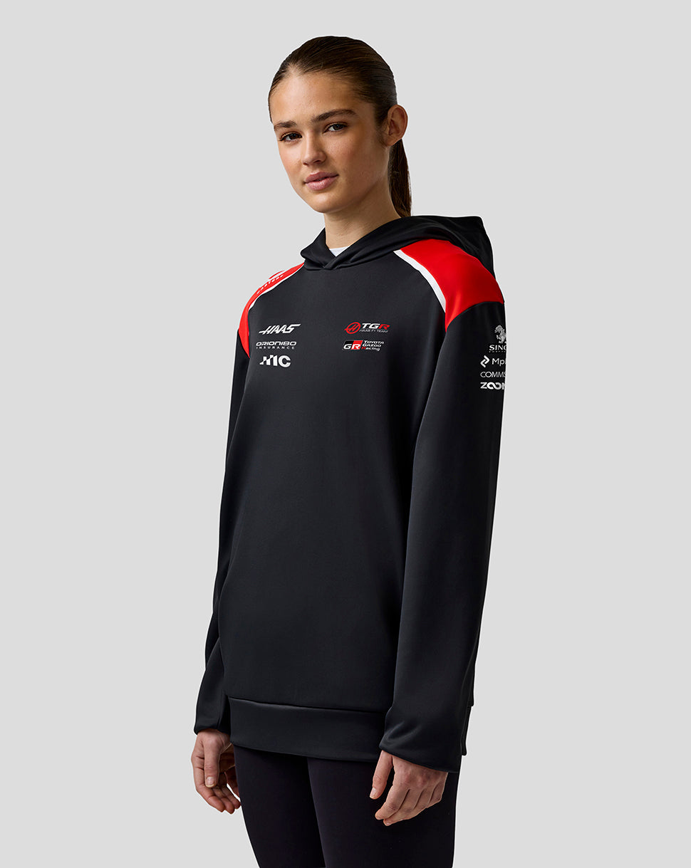 Person wearing a black hoodie with red and white accents on a gray background