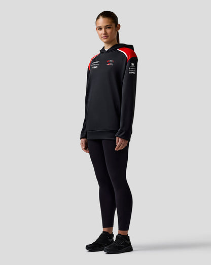 Person wearing a black tracksuit with red accents on a light gray background