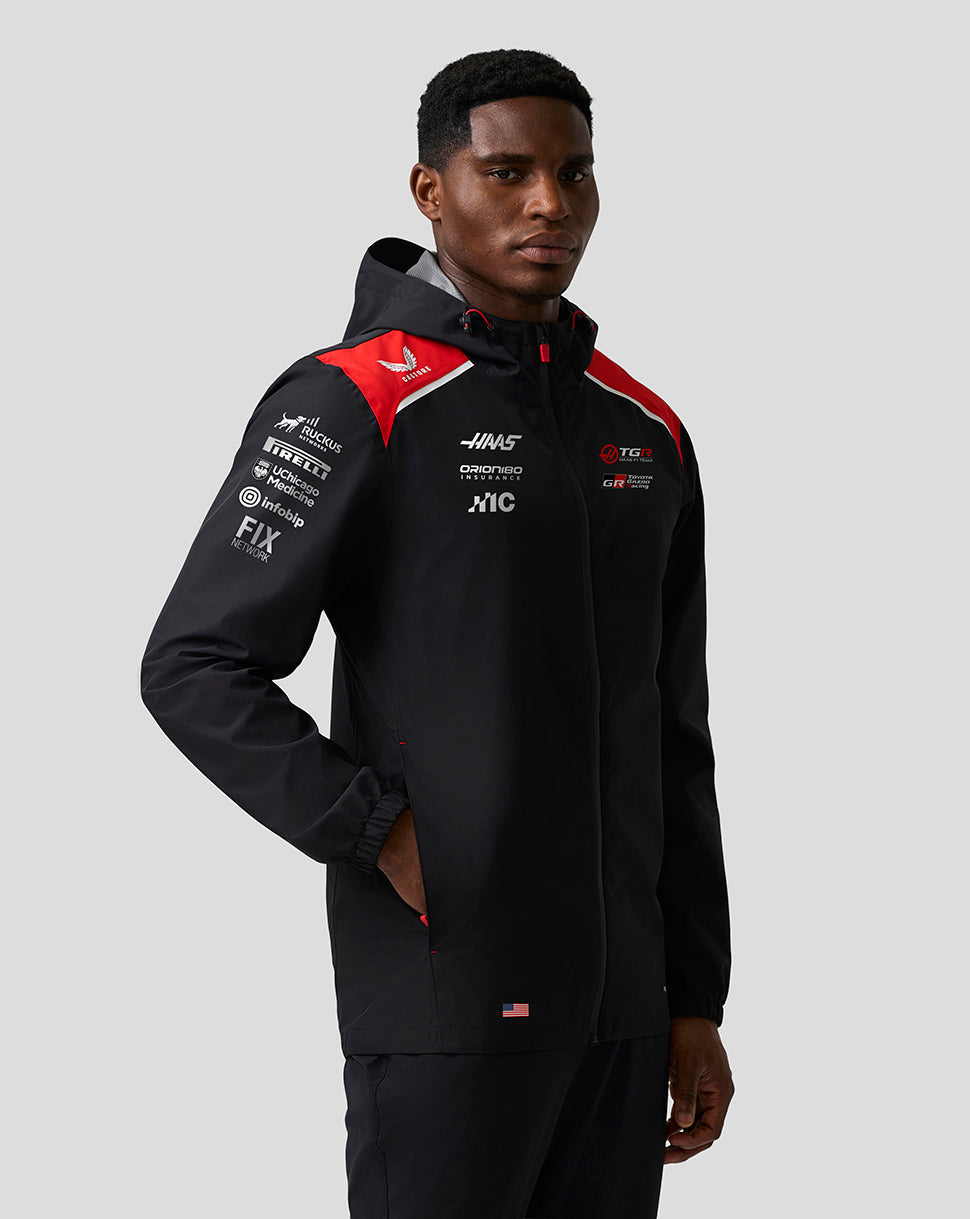 Person wearing a black jacket with red and white accents on a gray background