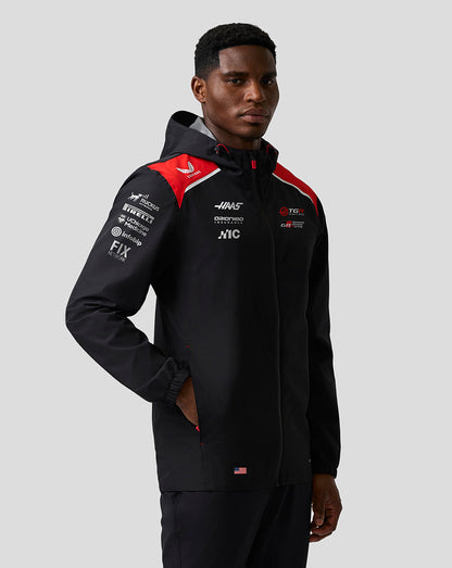 Person wearing a black jacket with red and white accents on a gray background