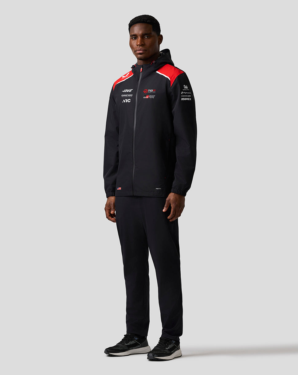 Person wearing a black tracksuit with red accents on a white background