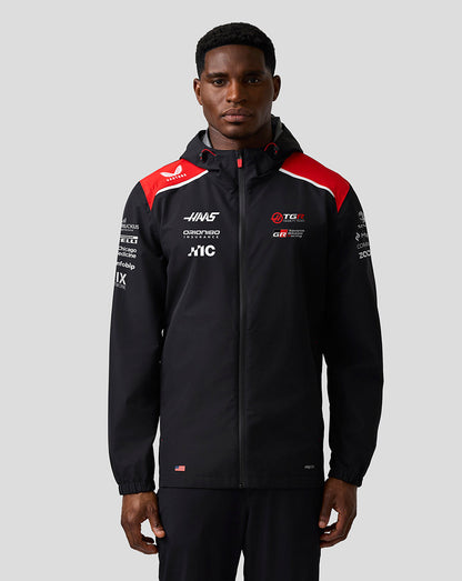 Person wearing a black jacket with red and white accents on a gray background